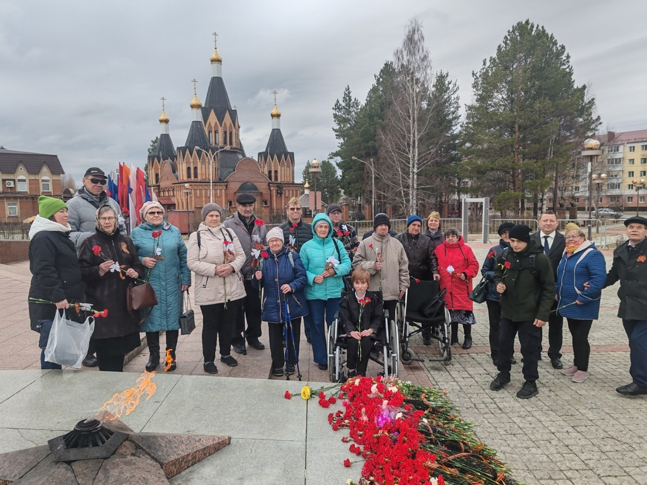 На фото члены ВОИ с гвоздиками в руках рядом с Мемориалом Памяти